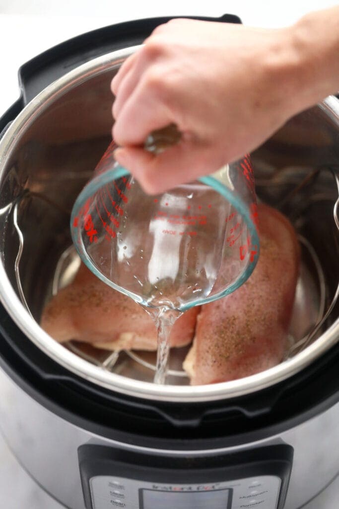 water being poured in the instant pot for instant pot shredded chicken.