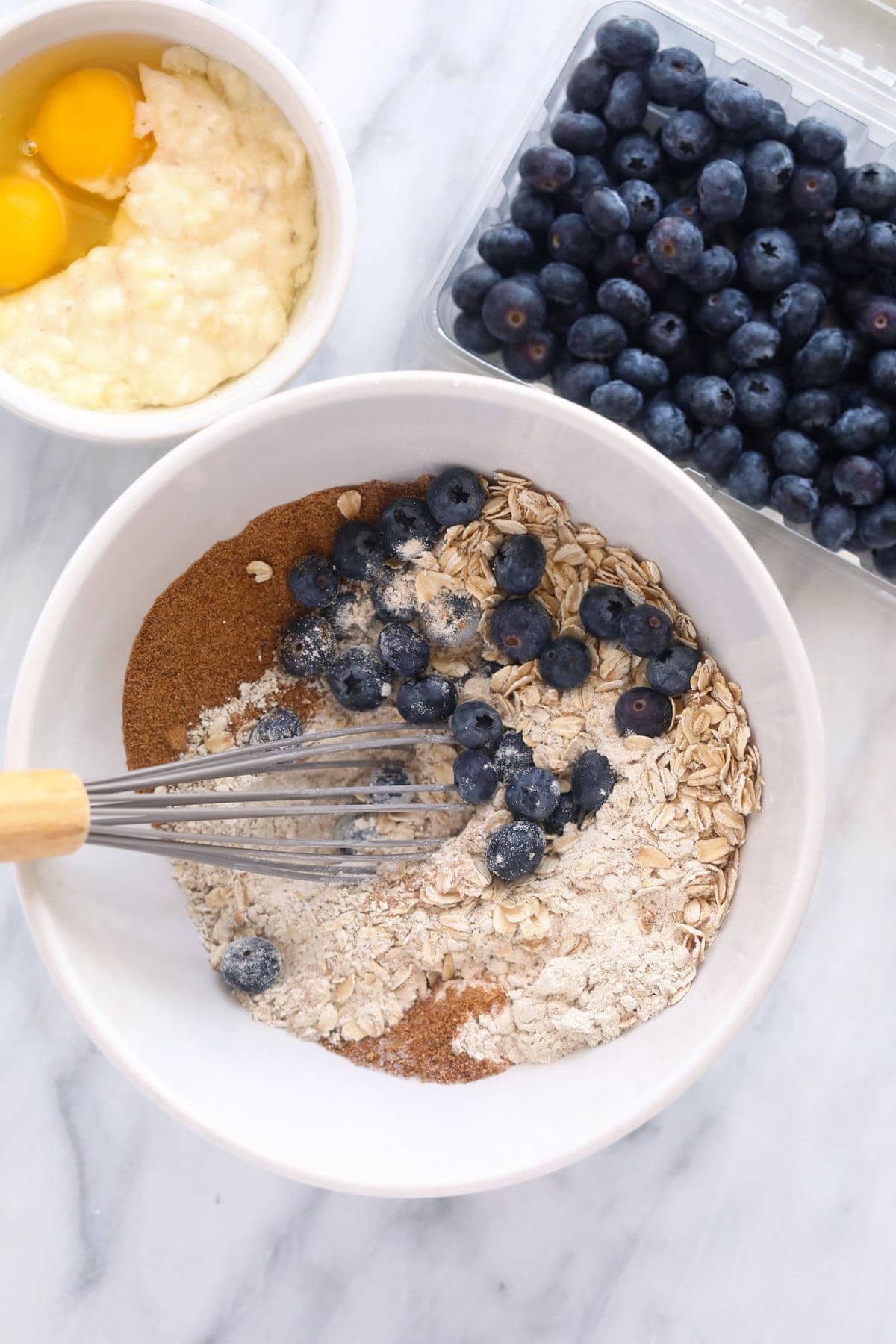 blueberry oatmeal muffin ingredients in a bowl, ready to be mixed together