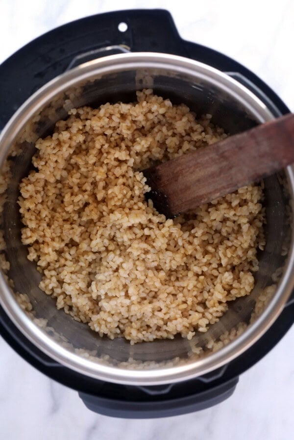 brown rice in an instant pot with a wooden spoon.