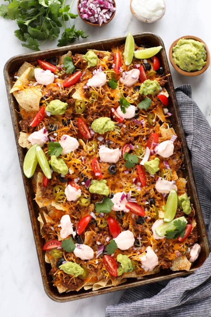 beef nachos on baking sheet with guacamole