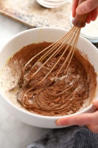 a person mixing chocolate in a bowl with a whisk.