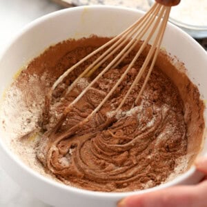 a person mixing chocolate in a bowl with a whisk.