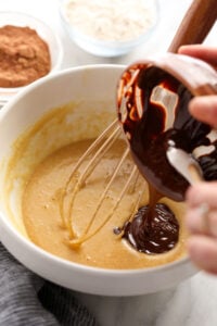 a person whisking a chocolate sauce into a bowl.