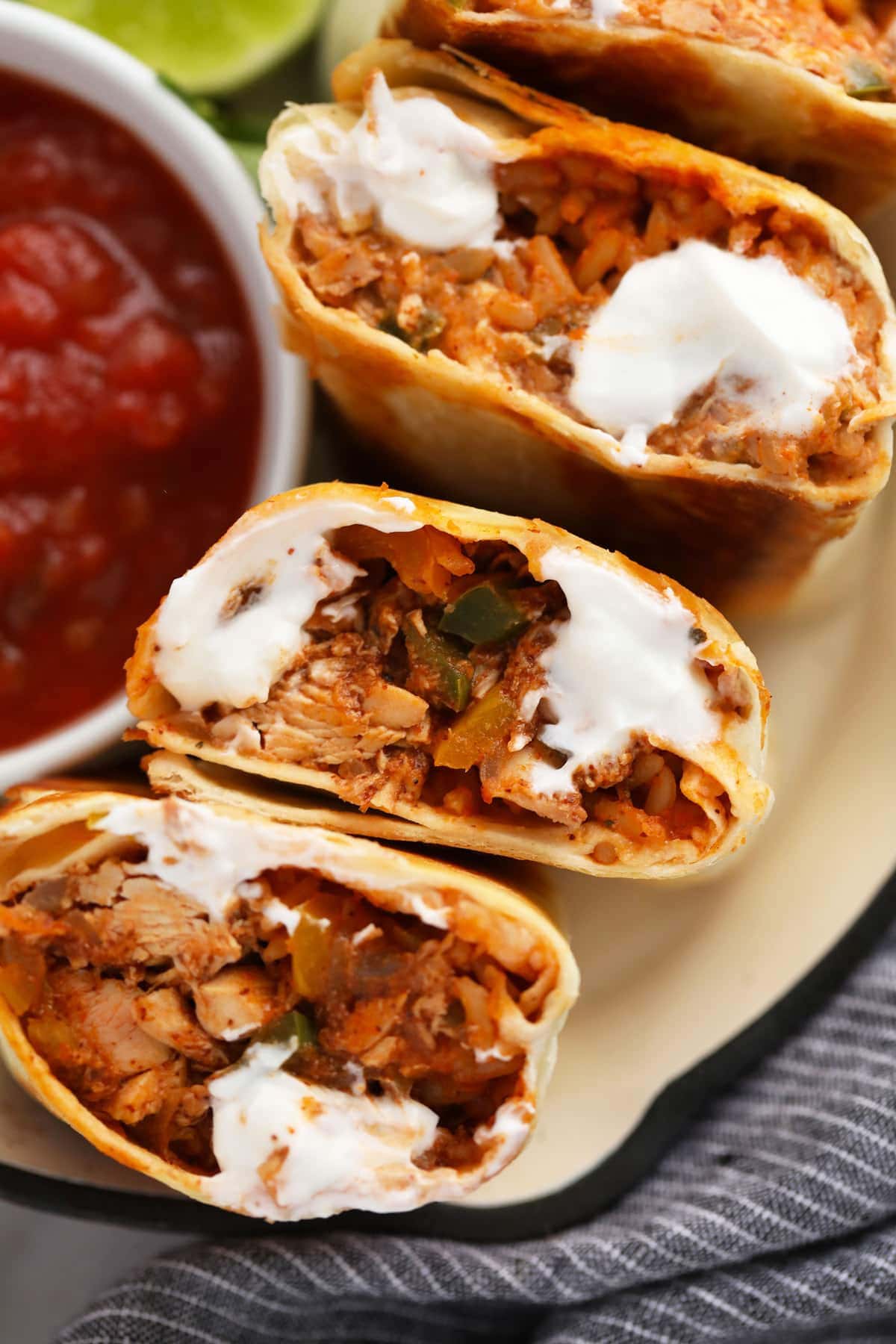 shredded chicken burritos cut in half and topped with sour cream.