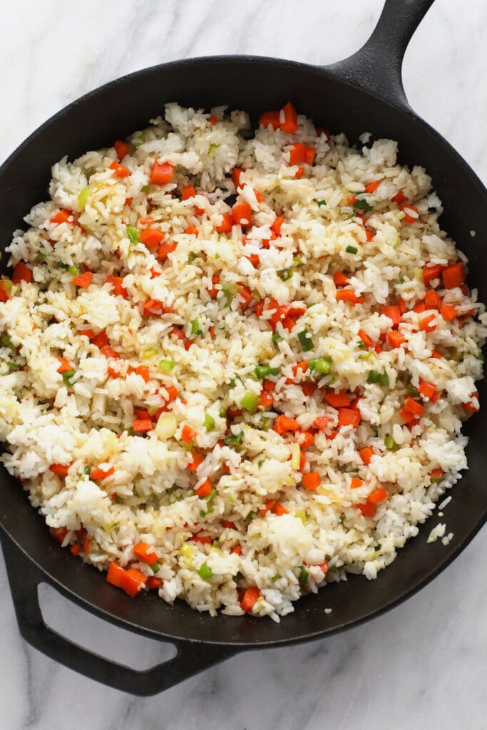 frying rice and veggies in cast iron pan