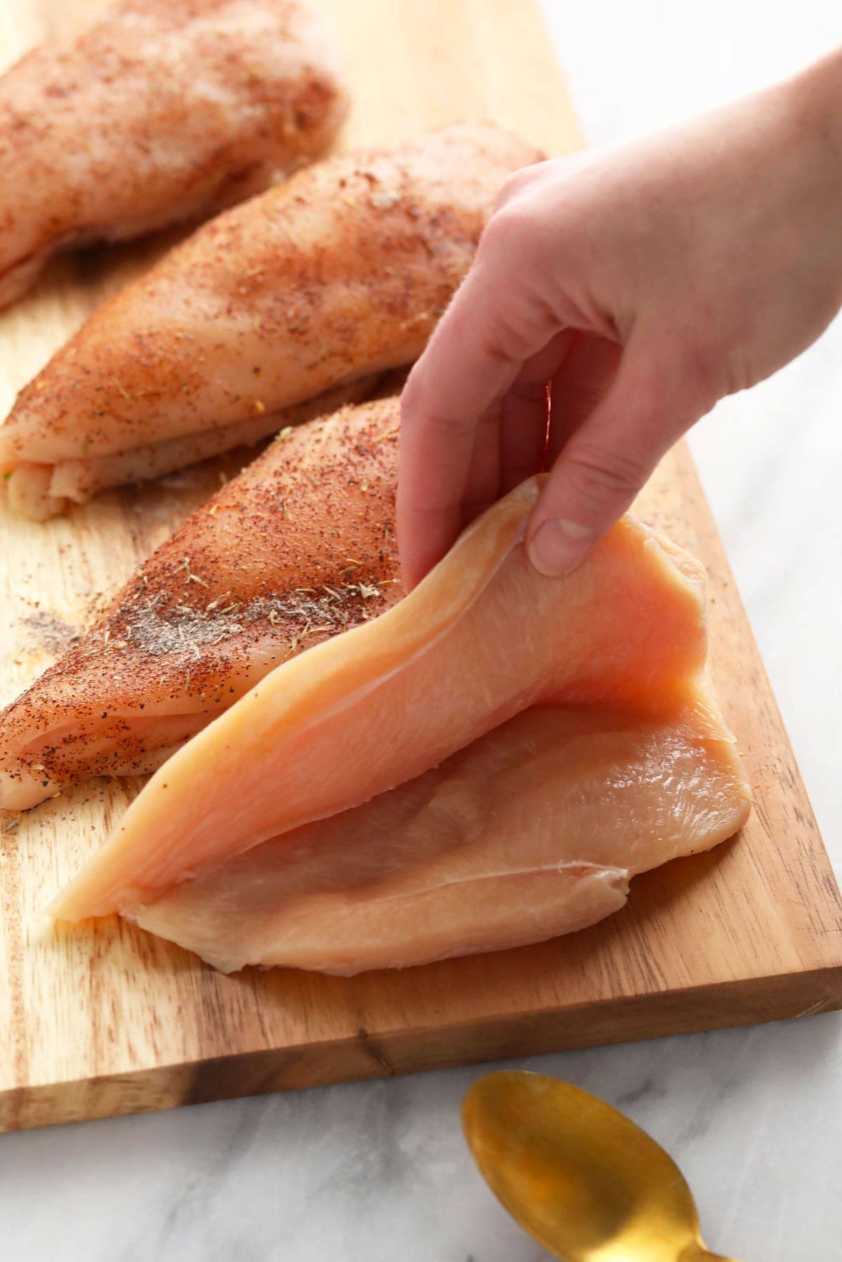 raw chicken breast cut open, ready to be stuffed with broccoli and cheese filling.