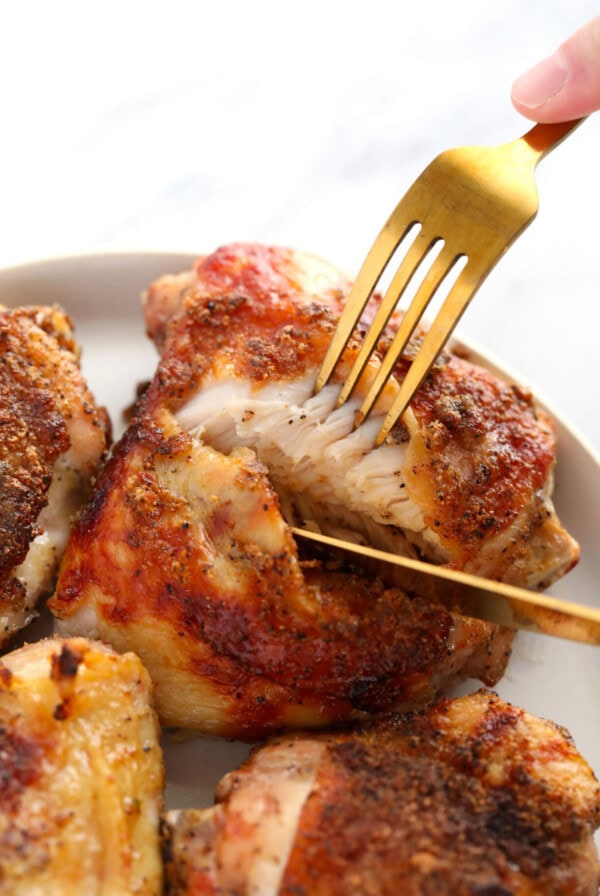 a person holding a fork on a plate of chicken breasts.