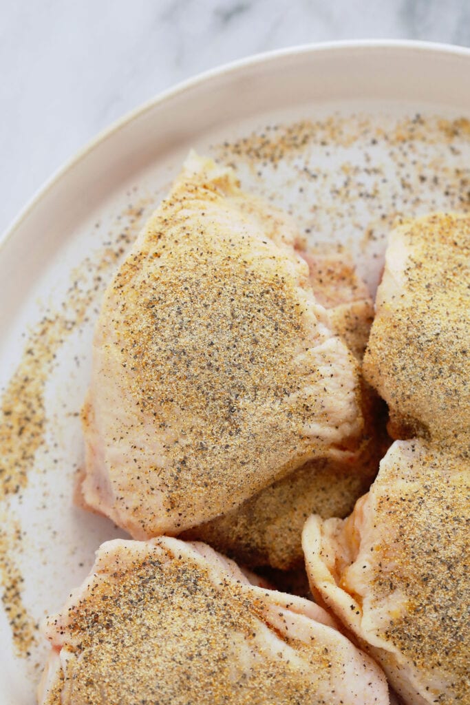 Raw chicken thighs with seasonings. 