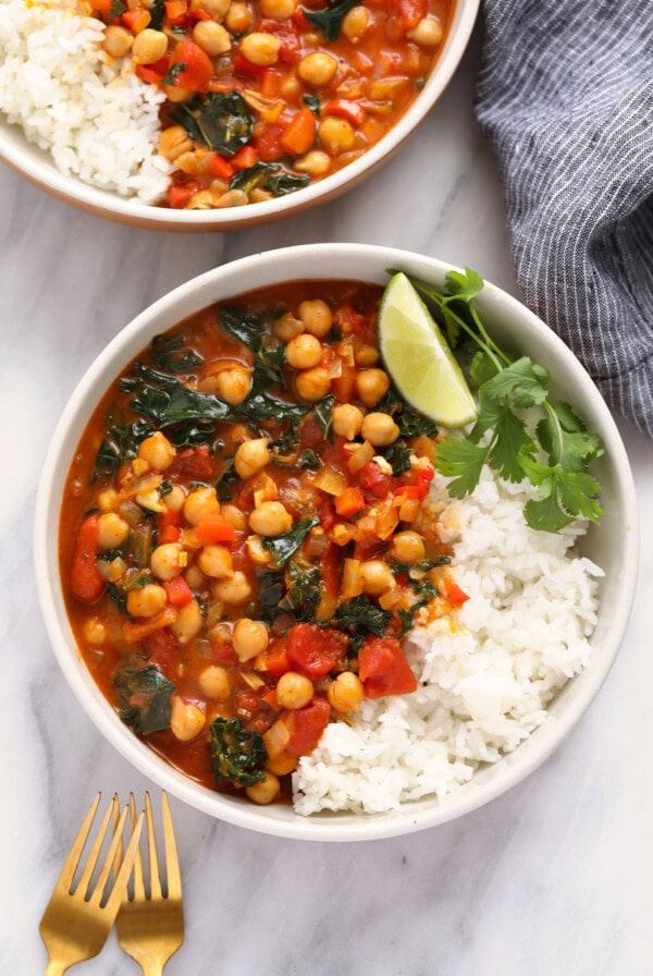 Two bowls of chickpea stew with rice and spinach, also known as chickpea curry.