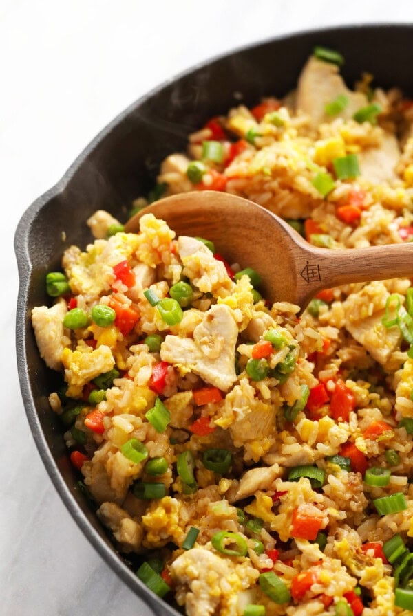 chicken fried rice in a skillet with a wooden spoon.