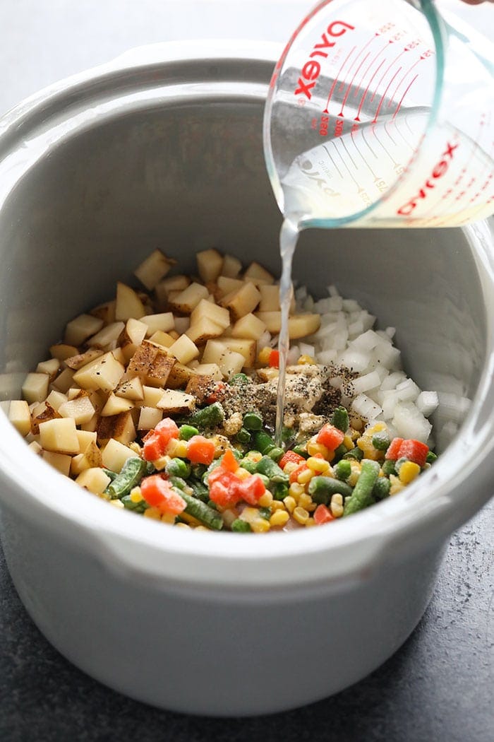 pouring liquid into slow cooker with soup