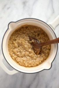 Oatmeal in a pot with a wooden spoon.