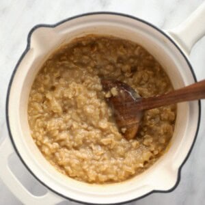 Oatmeal in a pot with a wooden spoon.