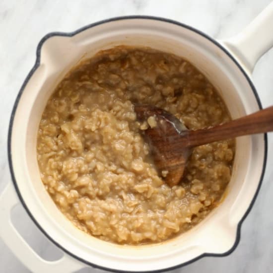 Oatmeal in a pot with a wooden spoon.