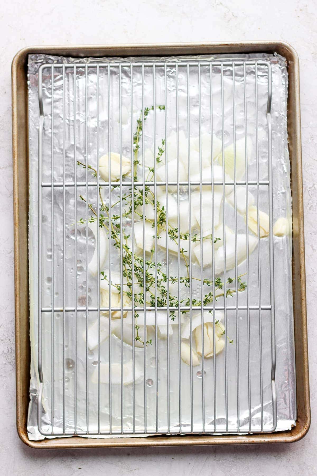 Onion and thyme on a baking sheet.