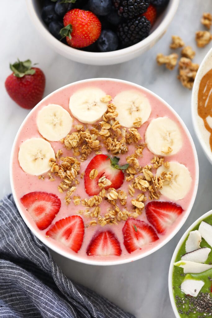 strawberry smoothie with banana slices, granola, and strawberries