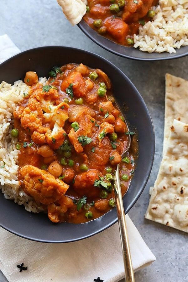 two bowls of curry with rice and naan.