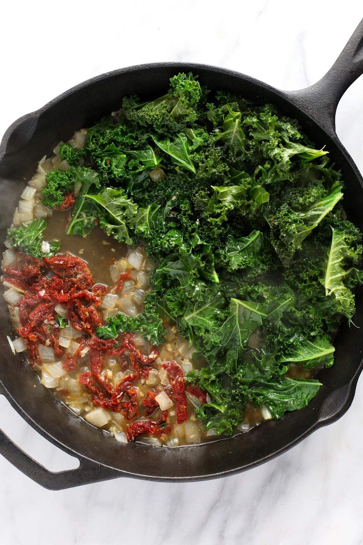 sauteed veggies in a cast iron skillet for creamy tuscan chicken and gnocchi