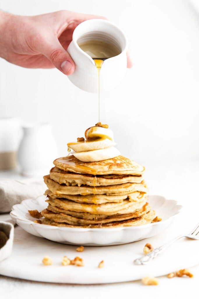 pouring syrup onto banana pancake recipe.