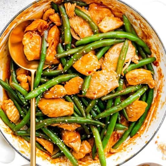 Kung Pao Chicken and green beans in a pan with sesame seeds.
