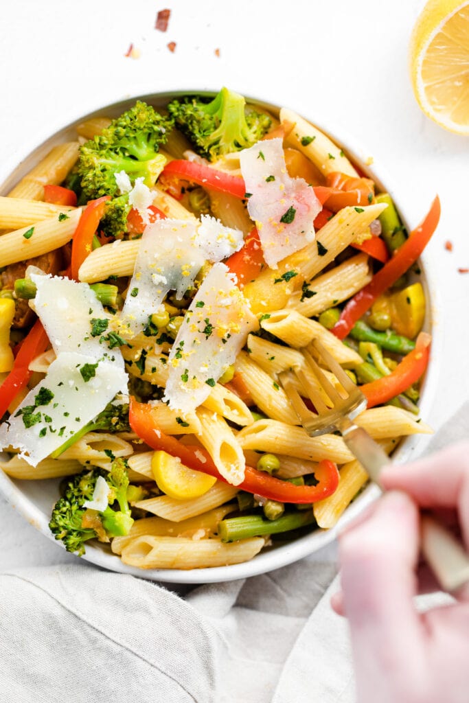 pasta primavera in a bowl topped with parmesan cheese