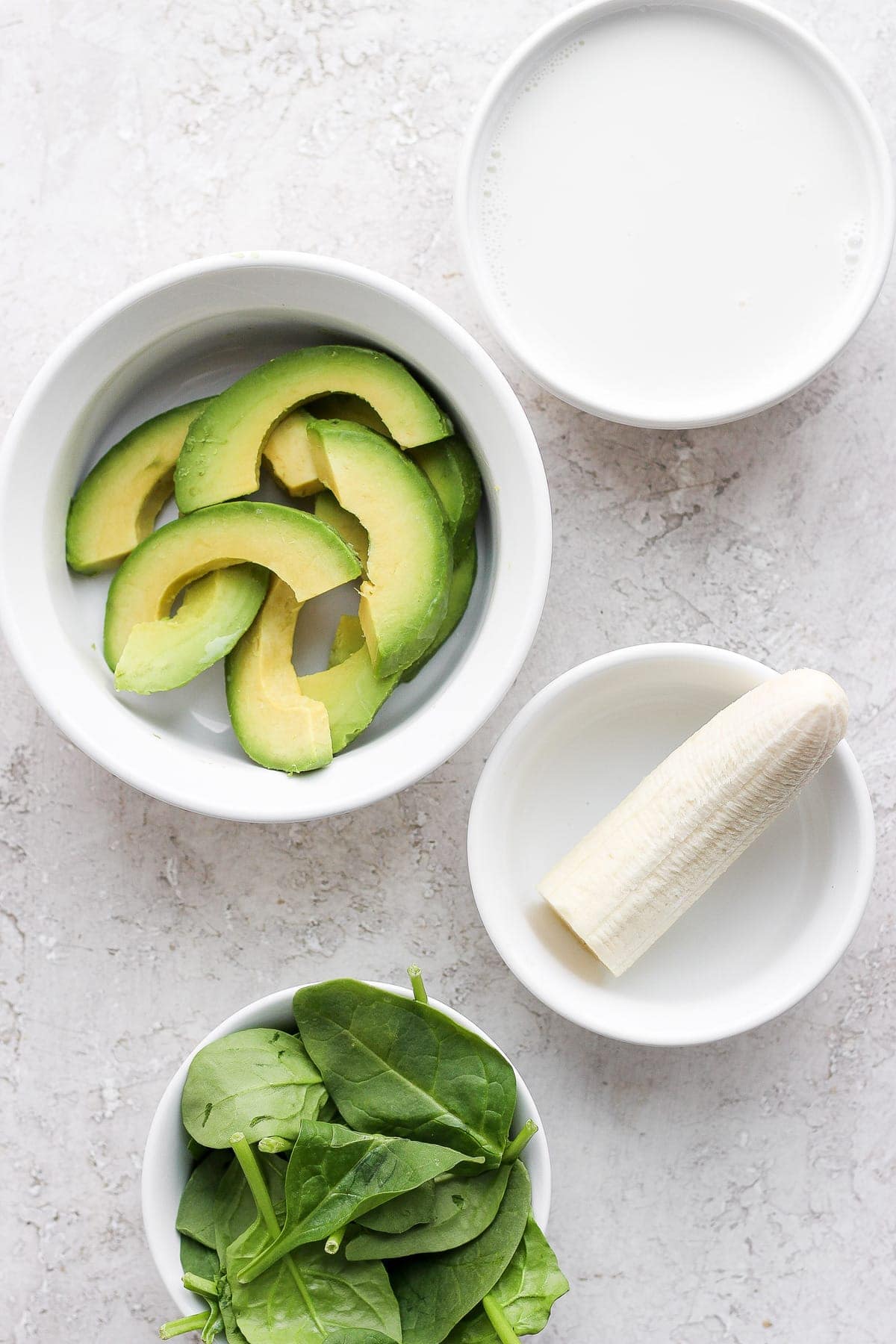 avocado smoothie ingredients in bowls, ready to be added to a blender