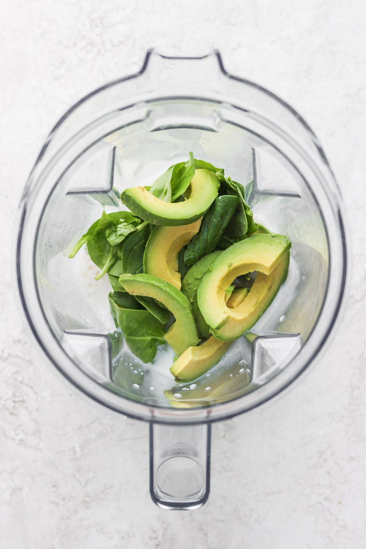 avocado smoothie ingredients in a blender, ready to be blended