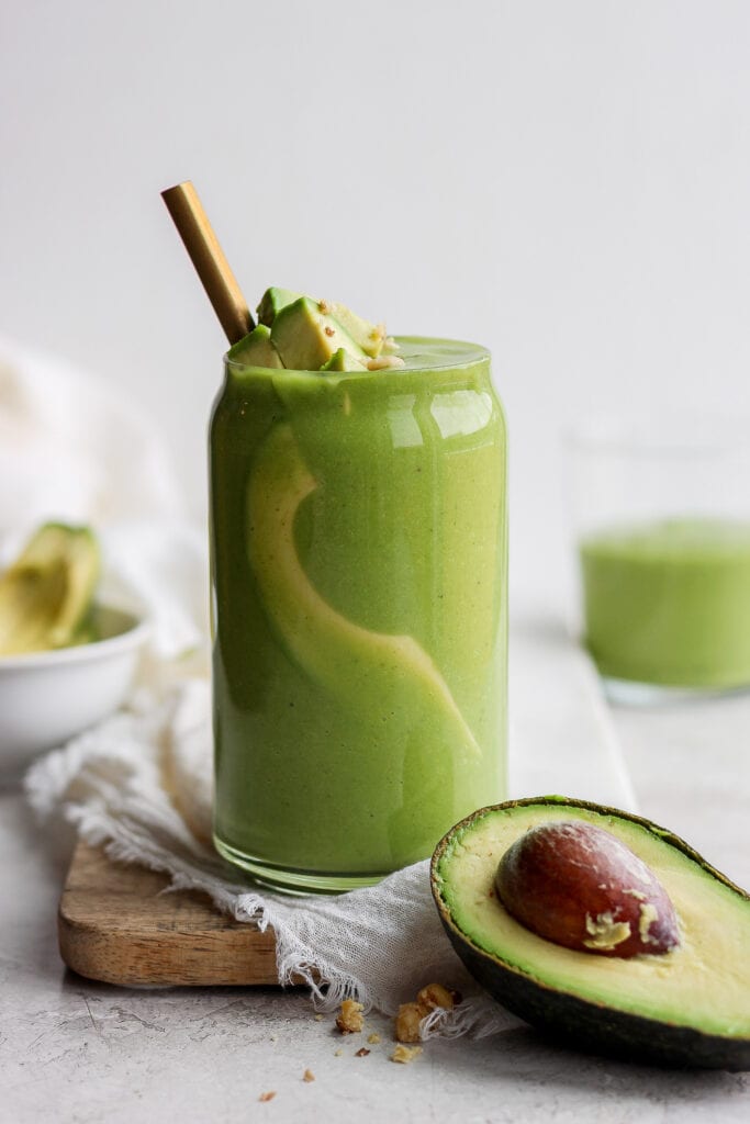 avocado smoothie topped with sliced avocado in a glass