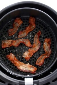 Bacon is being cooked in an air fryer.