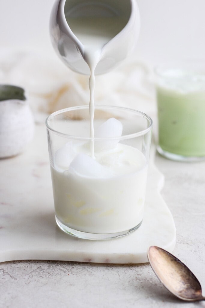 Pouring almond milk and maple syrup mixture over ice. 