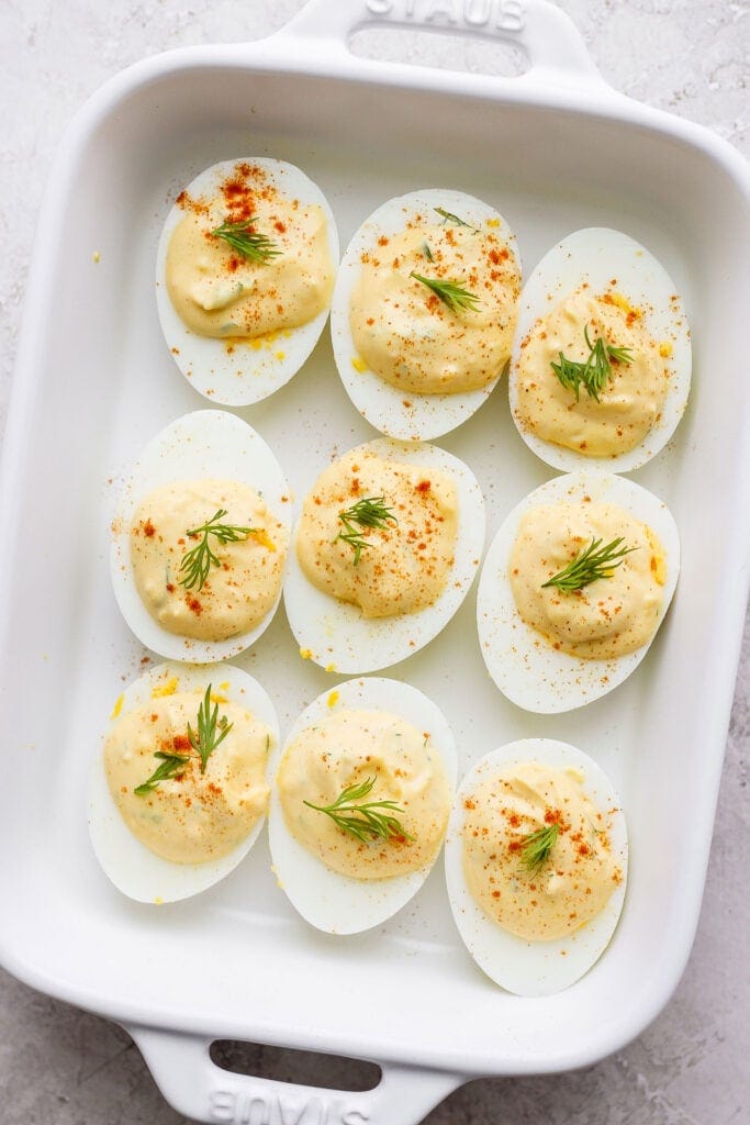 easy deviled eggs in a dish garnished with paprika and fresh dill