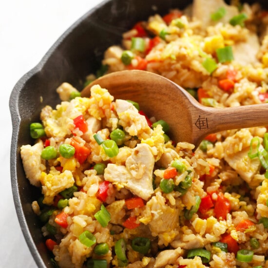 chicken fried rice in a skillet with a wooden spoon.