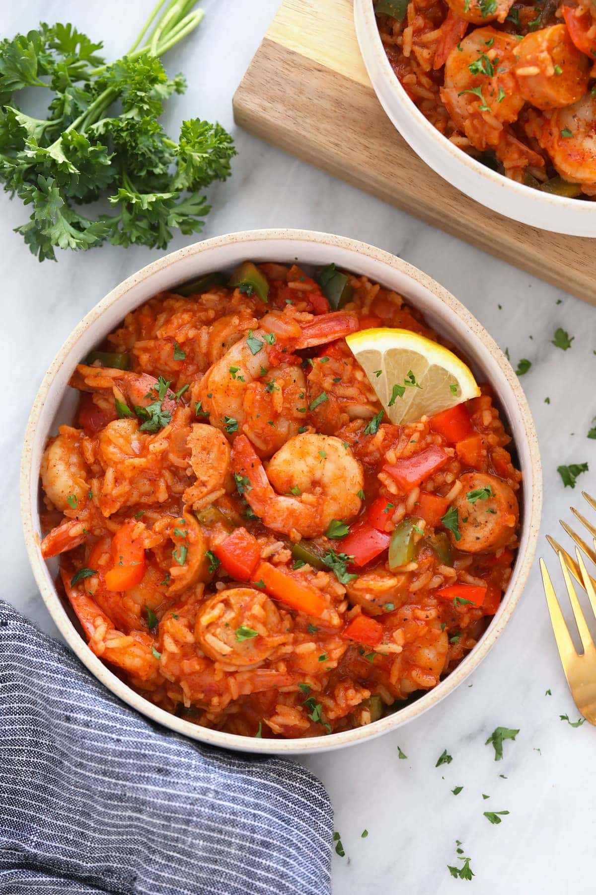 A bowl of jambalaya with a lemon slice. 