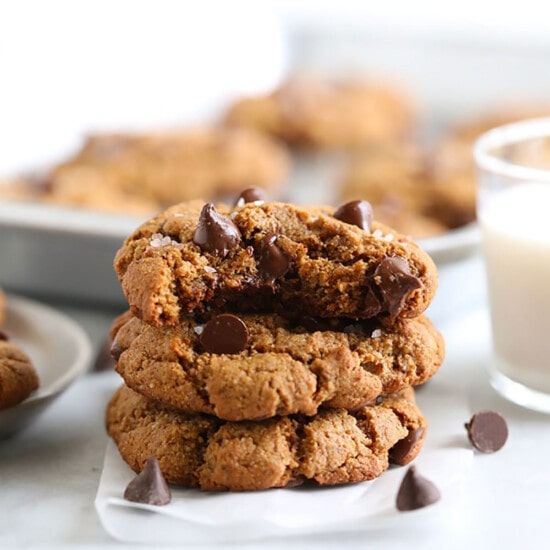 a stack of chocolate chip cookies with a glass of milk.
