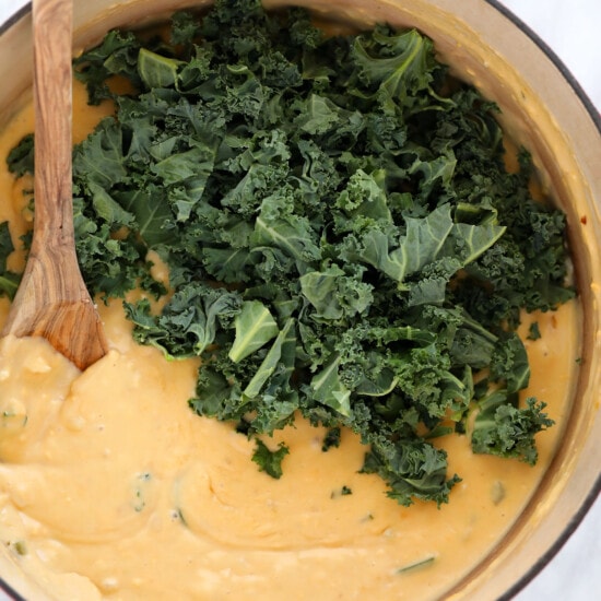 A pan with kale and a wooden spoon.