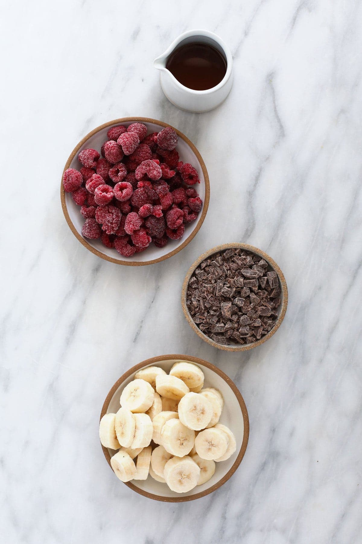 ingredients for raspberry chocolate chunk banana nice cream, ready to be added to a food processor