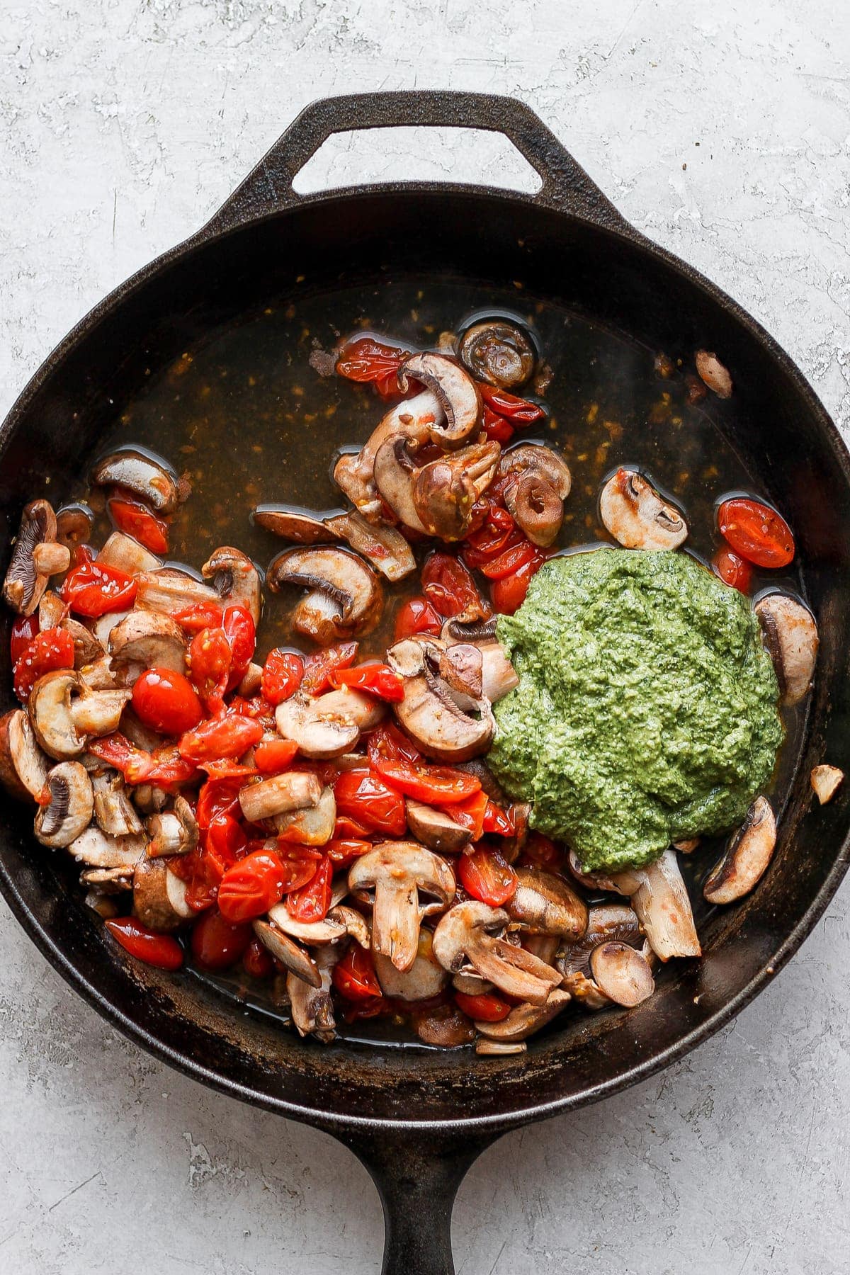 Pesto and vegetables in a cast iron skillet. 