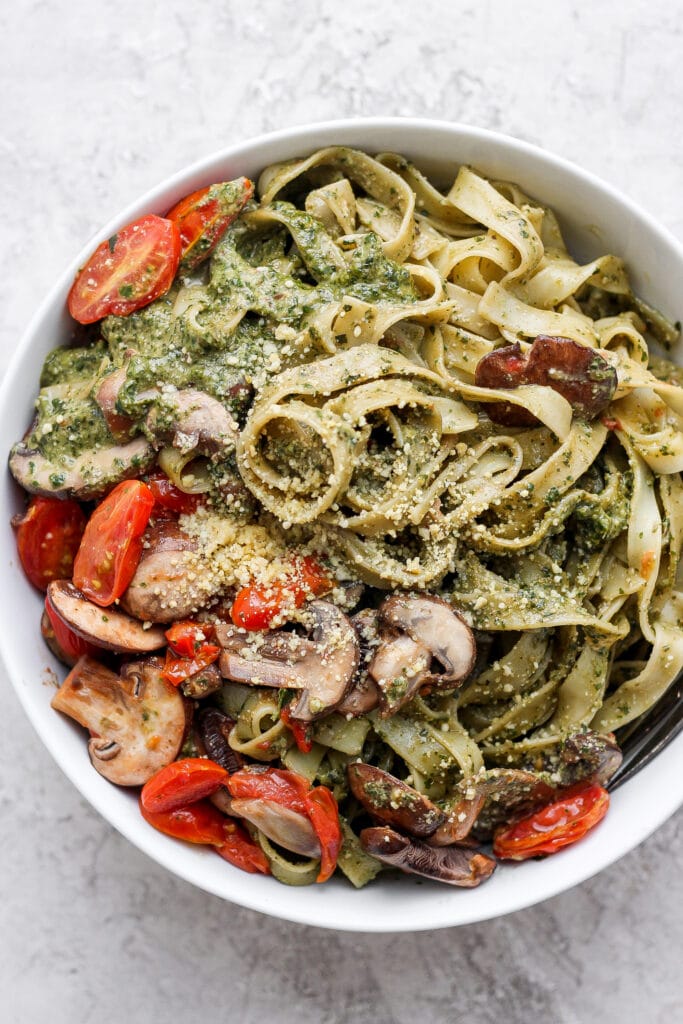Vegan pesto pasta with tomatoes, mushrooms, pesto, and vegan parmesan. 
