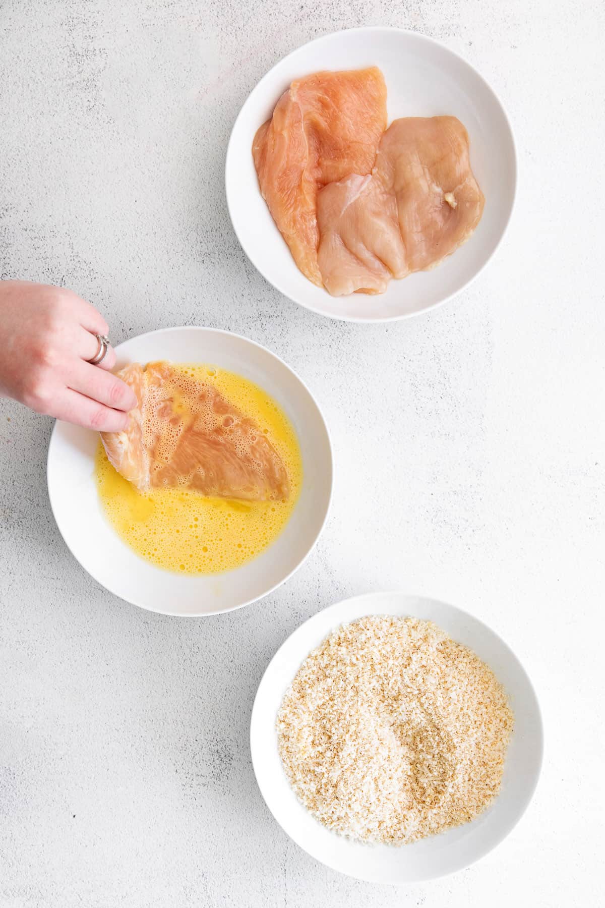 dipping chicken breast in egg wash.