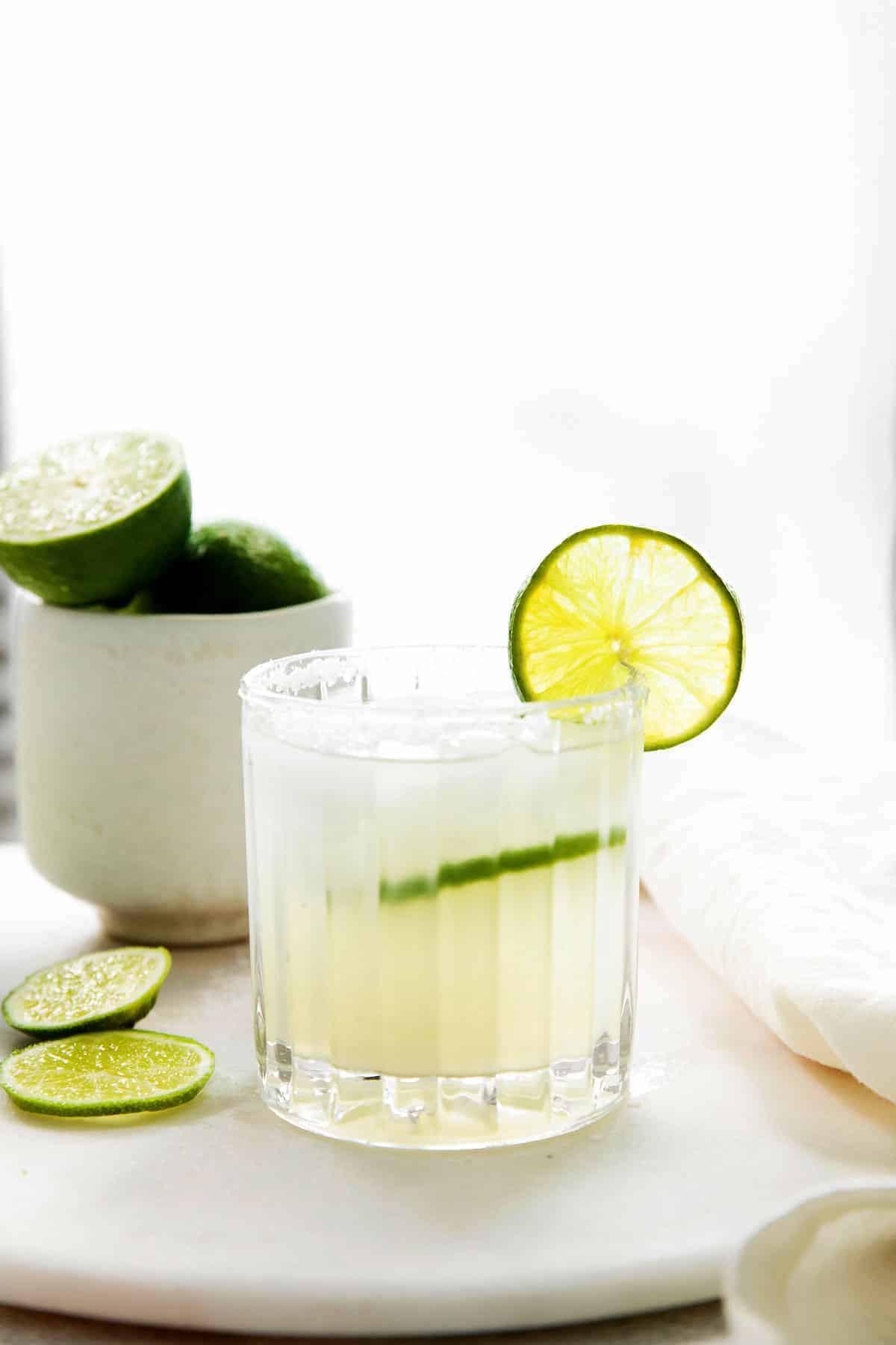 A cocktail glass full of margarita with a fresh lime slice. 