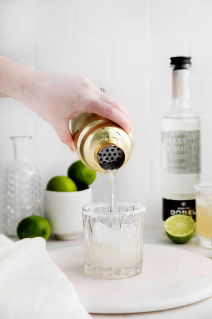 Pouring the margarita into a cocktail glass. 
