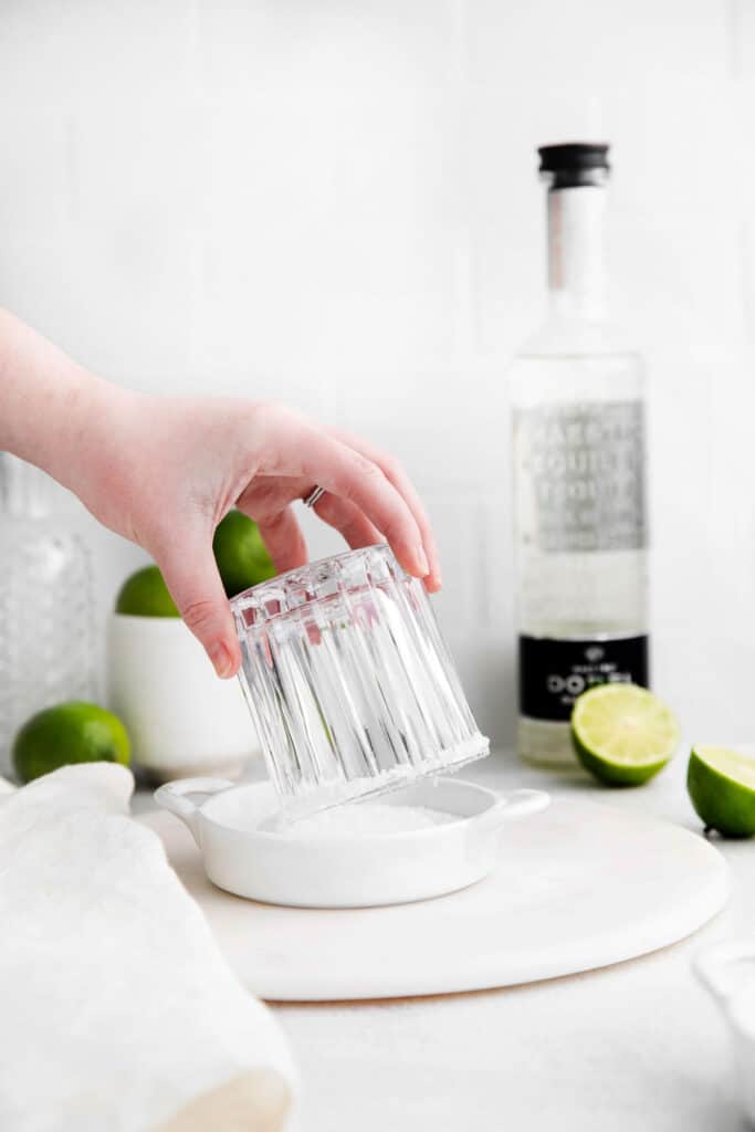 Dipping the rim of a margarita glass into salt. 