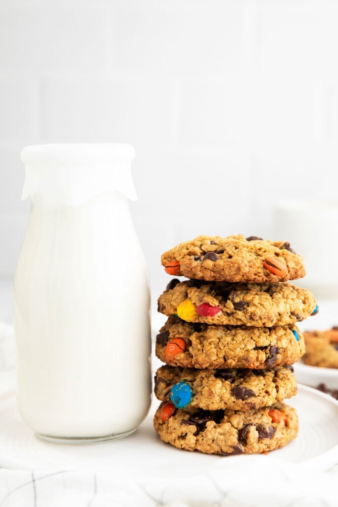 These flourless monster cookies are made with oats, peanut butter, chocolate chips, and M&M's. They're soft, chewy, and so delicious. stack of cookies next to milk