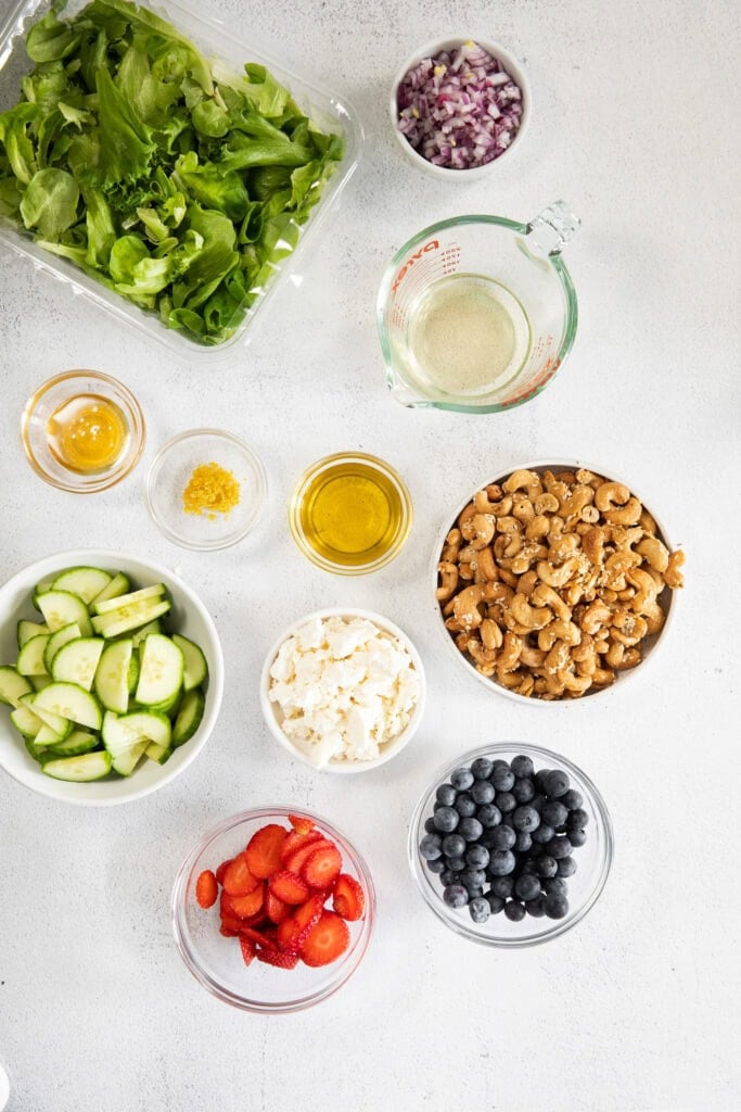 All of the ingredients for a spring mix salad in small bowls. 