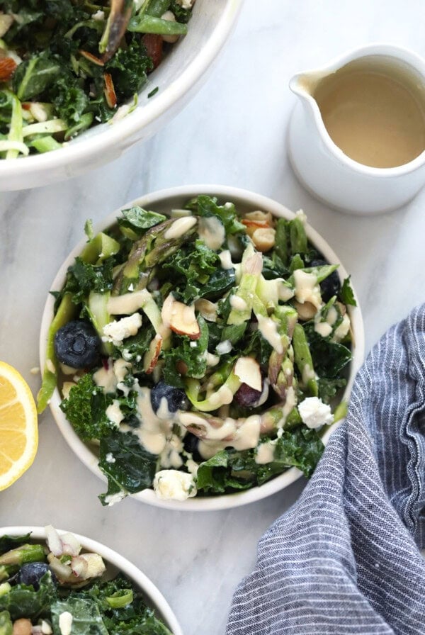 a bowl of kale salad with blue cheese dressing and asparagus.