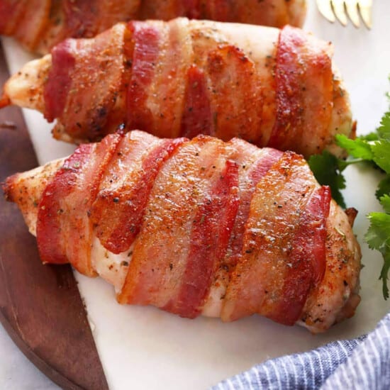 Bacon wrapped chicken breasts on a cutting board.