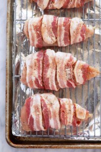Bacon wrapped chicken breasts on a baking sheet.