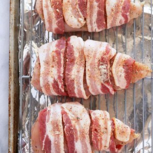 Bacon wrapped chicken breasts on a baking sheet.