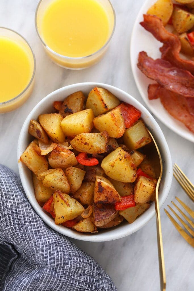 breakfast potatoes in a bowl, served next to a glass of orange juice