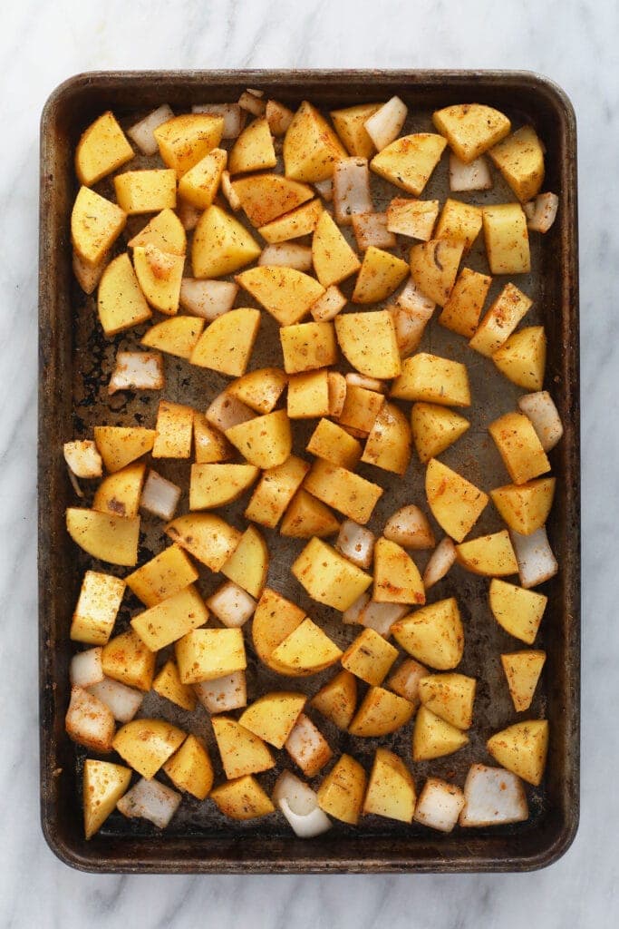 sliced breakfast potatoes on a baking sheet, ready to be baked